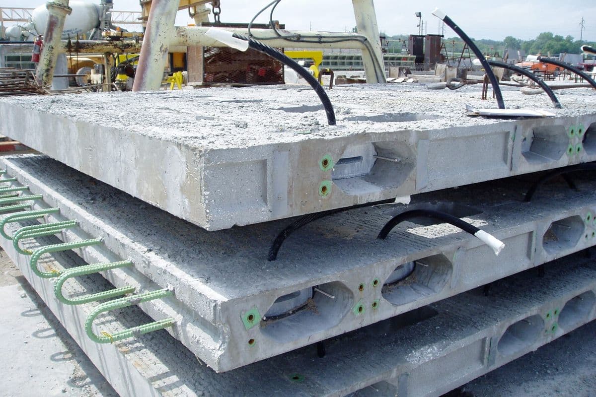 A stack of precast concrete bridge deck panels with rebar loops on the side, stored at a precast plant for an Iowa bridge project.